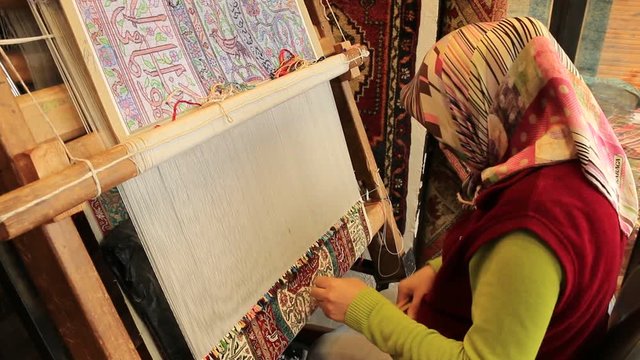 Muslim woman weaving handmade silk carpet