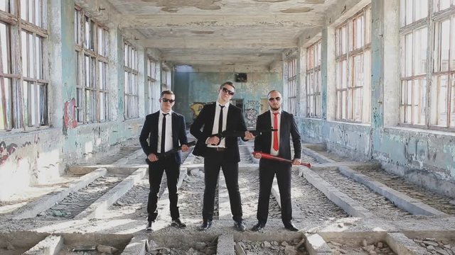three criminals with weapons in an abandoned building