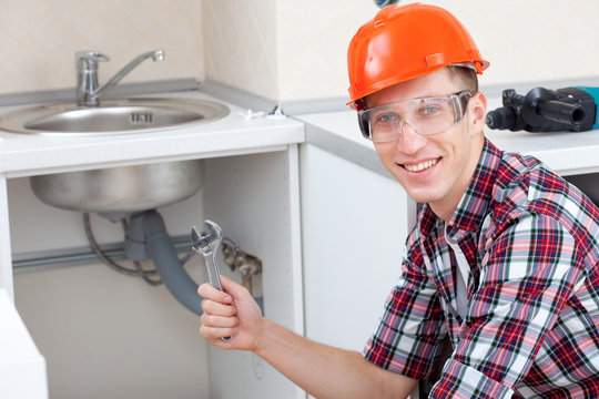 smiling plumber near the kitchen sink