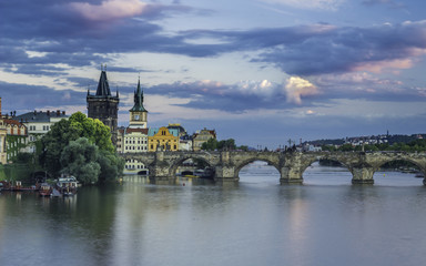 Magical view on the Vltava river, Charles bridge and its bridge towers  with blue and violet clouds.
