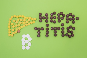 Figure or shape of human liver and the diagnosis of hepatitis B sign made of yellow, brown and white pills or tablets on a green paper background 