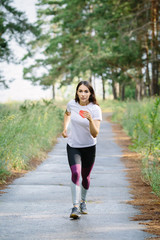Woman running in wooded forest area, training and exercising for trail run marathon endurance. Fitness healthy lifestyle concept.