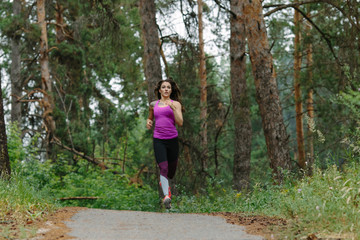 Woman running in wooded forest area, training and exercising for trail run marathon endurance. Fitness healthy lifestyle concept.