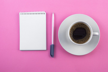 Obraz na płótnie Canvas White cup of coffee, notepad, pen on a pink background