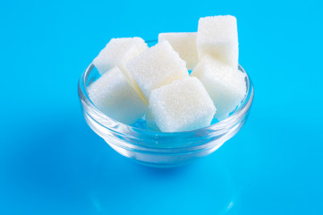 Sugar cubes in saucer on a blue background