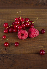 Raspberries and currants on a wooden background
