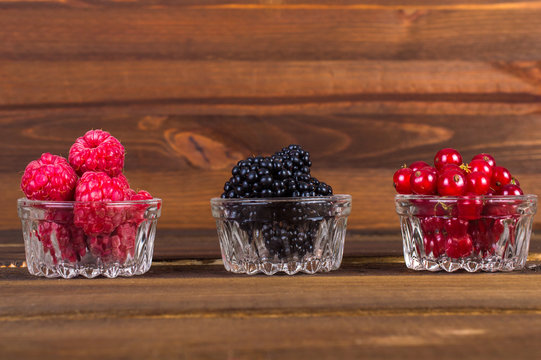 Wild berries in glasses on wooden background