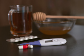 On the table are tea, thermometer, tablets and honey