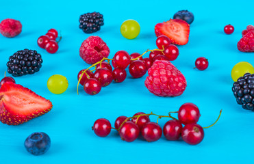 Various fresh berries and fruits on a blue background.