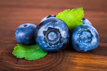Blueberries berries with leaves lie on a wooden table. Close-up.