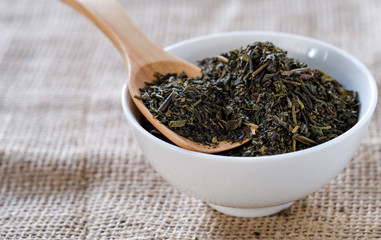 Tea on wooden spoon in white cup with sackcloth floor.