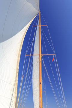 Segel und Mast eines Segelbootes unter blauem Himmel