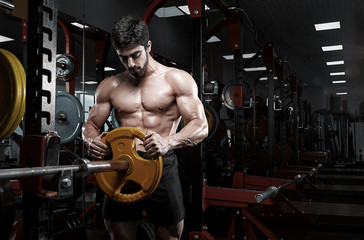 Fototapeta na wymiar Handsome bodybuilder guy prepare to do exercises with barbell