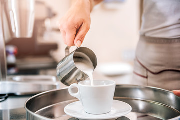 Fototapeta na wymiar Woman pouring milk in coffee