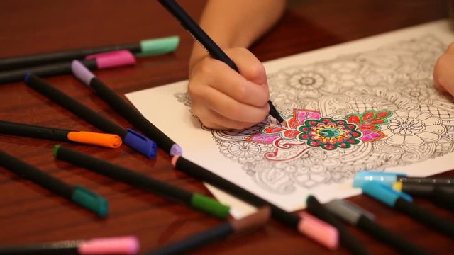 Childs hand painting anti stress colouring with colored felt pens, closeup