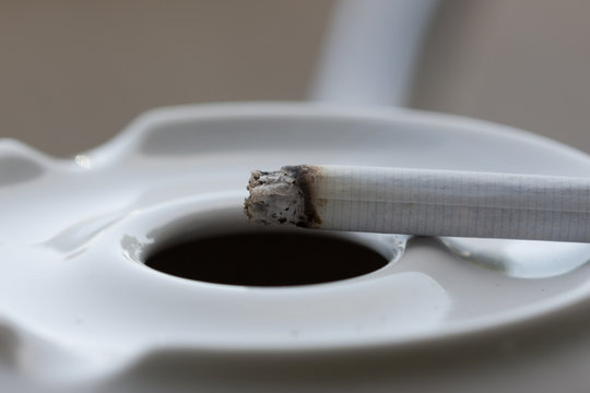  Cigarette burns close-up isolated on white ashtray