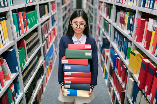 Junge Studentin mit einem Stapel B&uuml;cher
