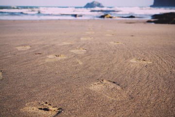 Footprints in the sand on Polzeath beach Vintage Retro Filter.