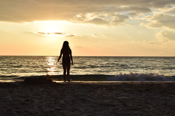 Fototapeta premium silhouette of a girl in the sunset light at the beach