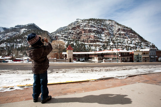 A little boy taking picture of a beautiful mountain covered with snow on Ouray,Colorado