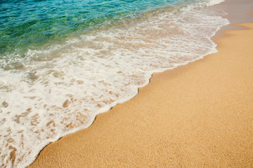 Background soft wave of Turquoise Sea with foam on sandy beach.