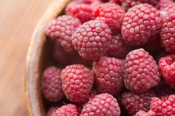 Macro photo of raspberry in wooden bowl, fresh berries close up, summer background
