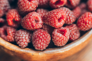 Macro photo of raspberry in wooden bowl, fresh berries close up, summer background