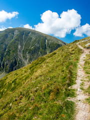 ascending mountain narrow path and funny shape clouds in parang mountains romania