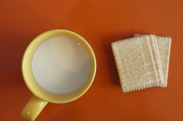 Cup with milk and crackers are isolated on a colored background