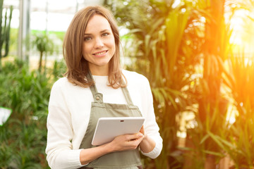 Young attractive woman working at the plants nursery using table