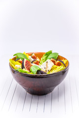 Homemade salad with figs, goat cheese and pine nuts on white background