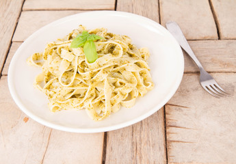 Tagliatelle with pesto decorated with basil on a wooden background