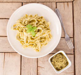 Tagliatelle with pesto decorated with basil on a wooden background