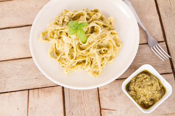 Tagliatelle with pesto decorated with basil on a wooden background