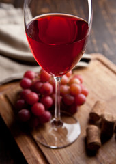 Glass of red wine and grapes on wooden board
