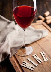 Glass of red wine on wooden board with letters and corks