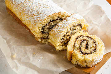 Biscuit roll with chocolate cream inside and powdered sugar on top. Roll is sliced
