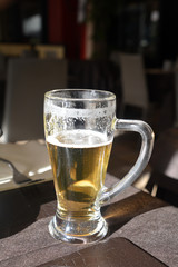 Glass of light beer on a restaurant table.