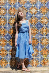 Portrait of beautiful elegant lady wearing hat near traditional azulejo tiles wall background