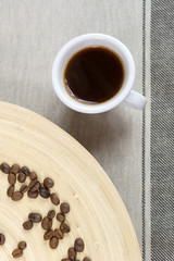 Coffee beans and coffee cup on wooden background. Top view.