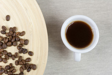 Coffee beans and coffee cup on wooden background. Top view.