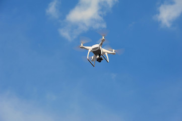 White drone quadrocopter with camera on blue sky background.
