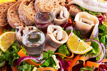 Traditional snacks salted herring with vegetables, onion, lemon, yellow lime, bread and two shots of vodka.