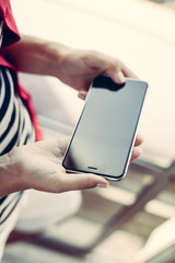 Close up of female hand holding mobile phone with blank screen, light background