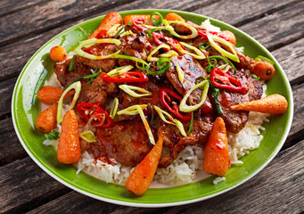 takeawy classic pork on rice with fried in sticky souce carrots, sprinkle of chillie and spring onion.