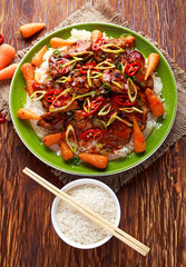 takeawy classic pork on rice with fried in sticky souce carrots, sprinkle of chillie and spring onion.