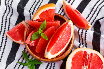 Juicy grapefruit Pilled pieces in wooden bowl with fresh mint lieves and slices.