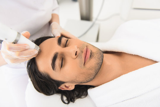 Relaxed guy getting electric facial massage