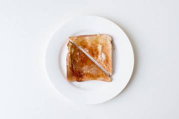 High angle view of toasted bread with butter and honey cut in half on white plate