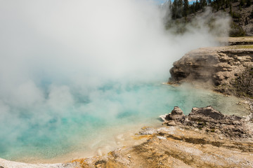 Light blue pool Excelsior geyser with steam rising from hot spring in Midway basin in Yellowstone...